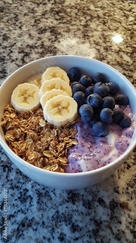 Delicious bowl of yogurt topped with fresh fruit and granola served on a kitc...
