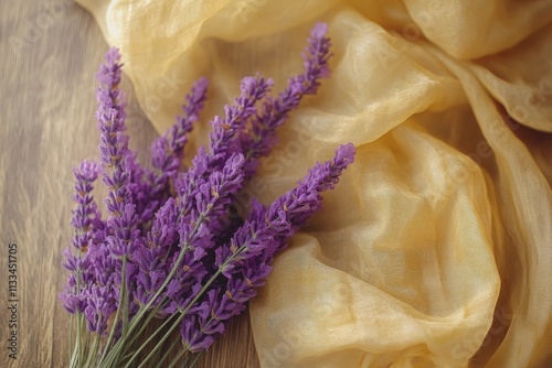 Purple lavender flowers arranged on soft yellow fabric with a natural wooden ...