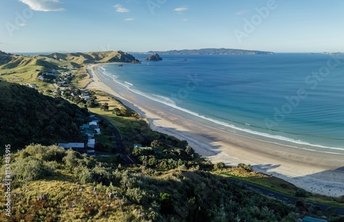 OPITO BAY, COROMANDEL PENINSULA, NEW ZEALAND, Coastal New Zealand town, houses nestled beside a beach, sunny day. photo