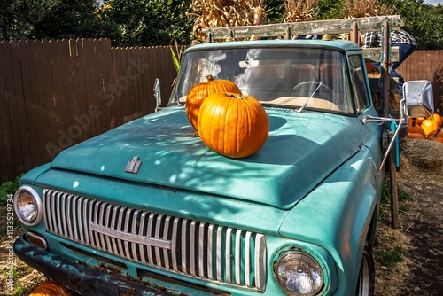 Two large, bright orange pumpkins sit atop a vintage turquoise pickup truck at a Fall festival in rural Virginia.