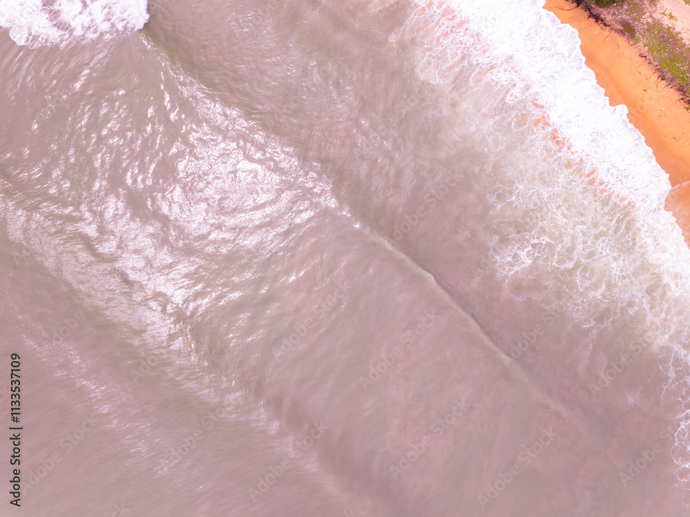 Fototapeta premium Amazing Top view colorful pink sand beach landscape background,Summer sea waves crashing on sandy shore seascape background,High angle view ocean nature beach background