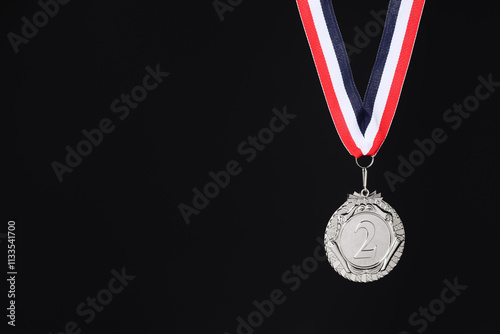 Silver medal with striped ribbon on black background, space for text