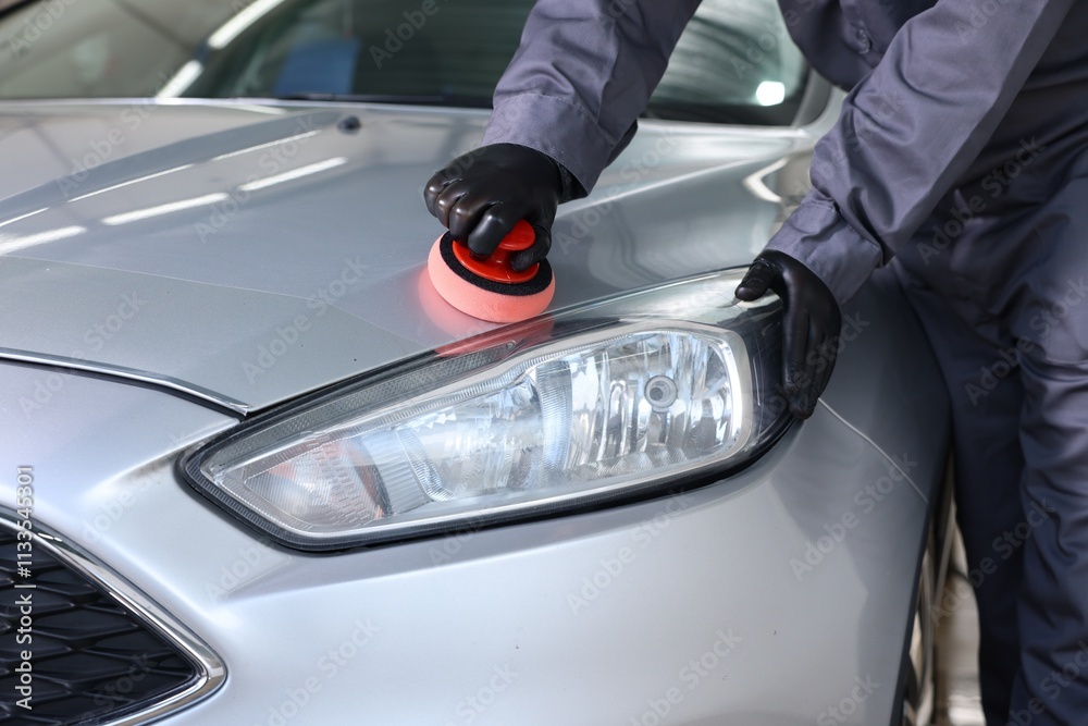 Fototapeta premium Man polishing car hood with sponge indoors, closeup