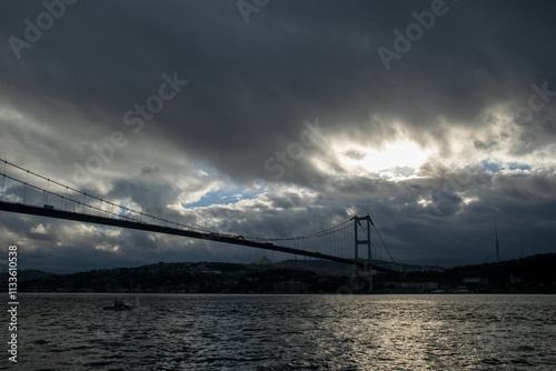 A boatman at sunrise in Ortakoy. View of the July 15 Martyrs Bridge (Bosphorus Bridge) and Camlica Mosque at sunrise.