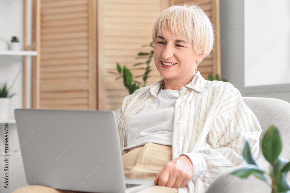Old woman with laptop sitting in armchair at home Old woman with laptop sitting in armchair at home