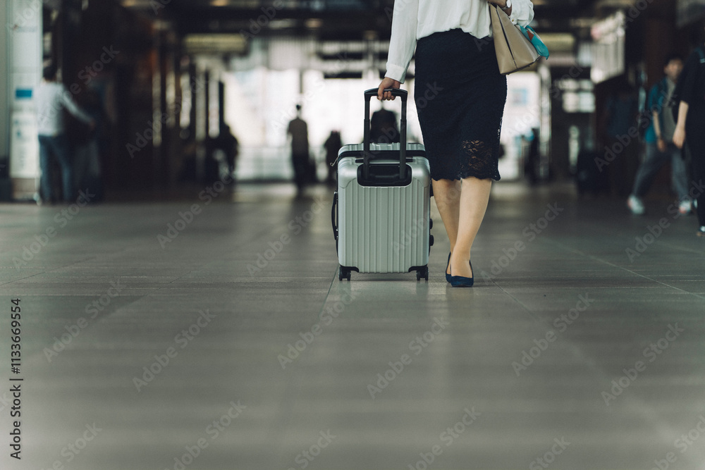 Fototapeta premium 駅でスーツケースを持った出張・旅行帰りの女性・ビジネスウーマンの足元