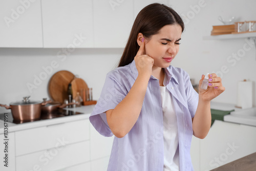 Young woman with ear drops ...