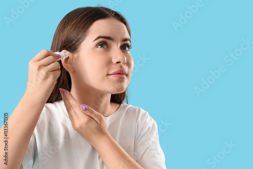 Young woman using ear drops...