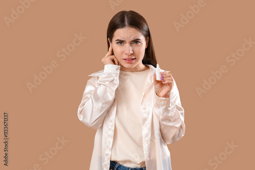 Young woman with ear drops ...