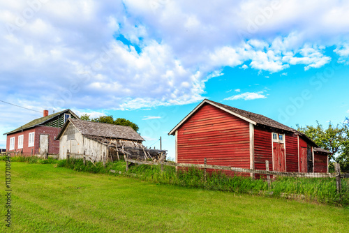 A red barn sits on a hillside next to a house