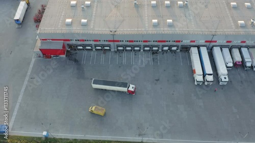 Modern logistics park with semi trucks at loading ramps, warehouse shipping and receiving area with multiple docking terminals aerial view