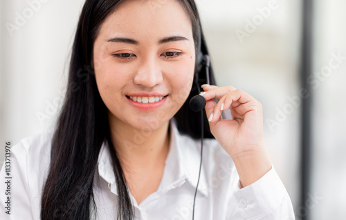 Smiling friendly asian female call-center agent with headset working on support call center agent hotline in the office