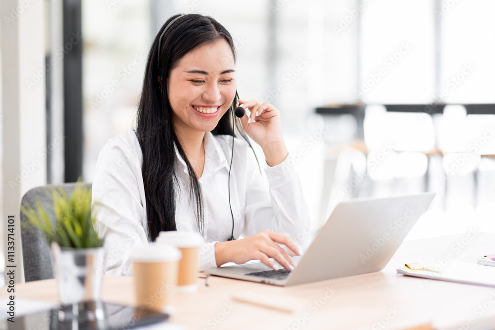 Smiling friendly asian female call-center agent with headset working on support call center agent hotline in the office Smiling friendly asian female call-center agent with headset working on support call center agent hotline in the office