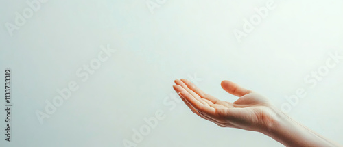 Close-up of human hand reaching out, conveying sense of connection and openness in minimalist setting.