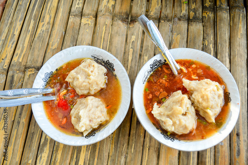 the delicious Two Mie Pentol Bakso or meatball soup in the White bowl with spoon and fork . Two Traditional Food of a Bakso Indonesian .Focus on meatball, Noisy, exposure, similar others