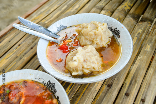 the delicious Two Mie Pentol Bakso or meatball soup in the White bowl with spoon and fork . Two Traditional Food of a Bakso Indonesian .Focus on meatball, Noisy, exposure, similar others