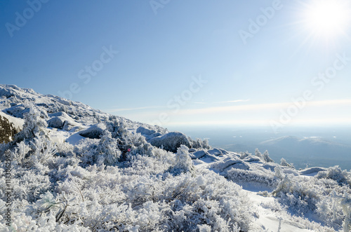 Winter landscape of Mount Monadnock in New Hampshire showcasing a snow-covered terrain and frost-covered trees under a clear blue sky