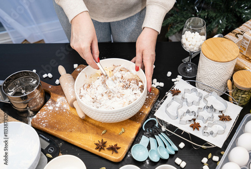 young woman hands knead the Doug for making gingerbread cookies on a wooden board, the table prepared to cook a Christmas holiday dessert