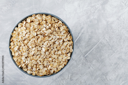 Bowl of Raw Rolled Oats on Textured Gray Background, Healthy and Nutritious Breakfast Ingredient, Copy Space