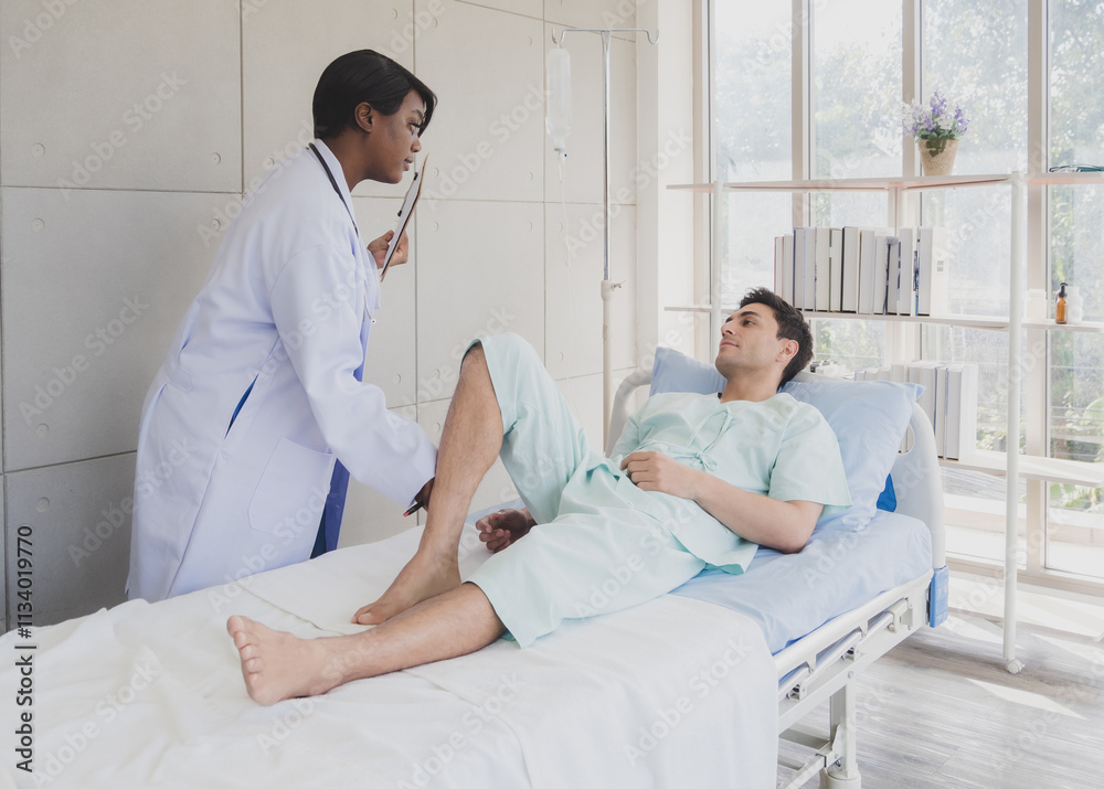 Obraz premium Patient caucasian man lying bed with woman doctor black people stand carer physical therapist two person talk help support and check treat sick person take care of your health in room hospital clinic