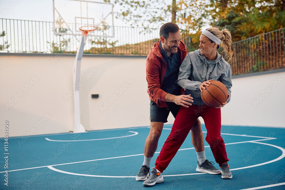 Obraz premium Happy athletic couple playing basketball outdoors.