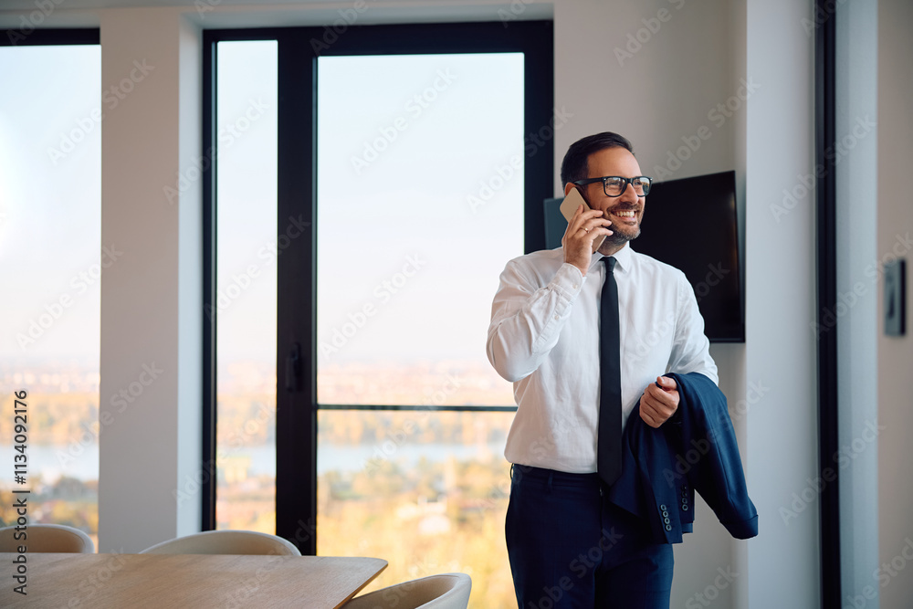 Fototapeta premium Happy businessman making phone call while working at corporate office.