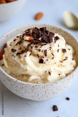 A bowl of creamy dessert topped with chocolate shavings and almonds.