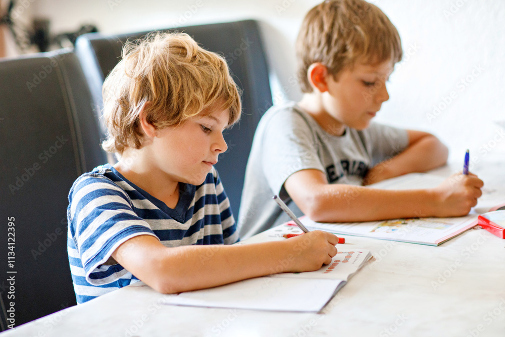 Two boys doing homework together. Brothers, siblings and twins learning at home. Elementary school students, children writing. Two boys doing homework together. Brothers, siblings and twins learning at home. Elementary school students, children writing.