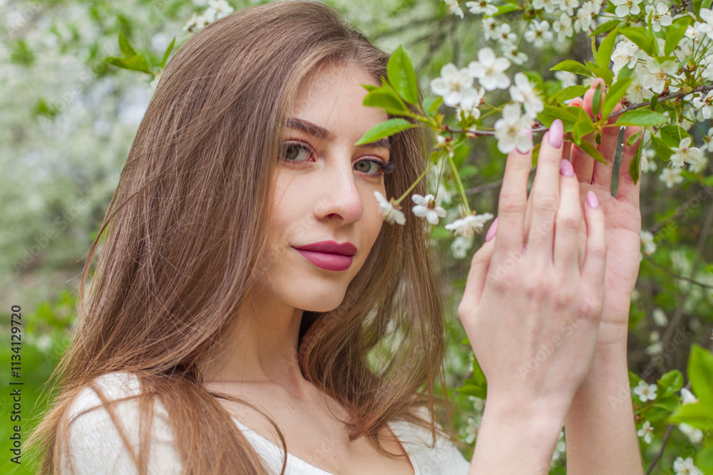 Beauty portrait of young woman with natural make-up and long smooth straight hair posing in spring flower garden park