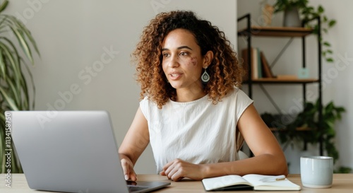 Focused young female entrepreneur working on laptop in modern home office