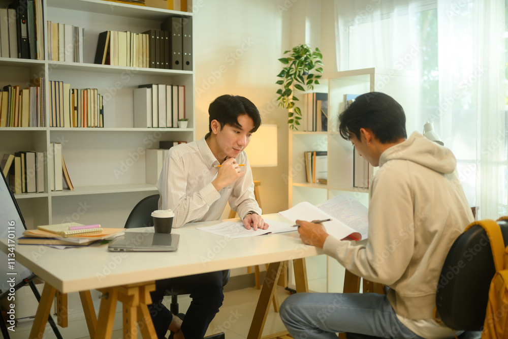 Asian male student studying with tutor at home. Education, knowledge and tutoring concept Asian male student studying with tutor at home. Education, knowledge and tutoring concept