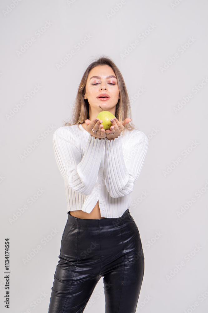 Attractive brunette young woman holding a yellow pear and standing on a white background. Copy space Attractive brunette young woman holding a yellow pear and standing on a white background. Copy space