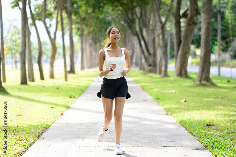 Smiling African athletic woman jogging along a pathway in a sunny park
