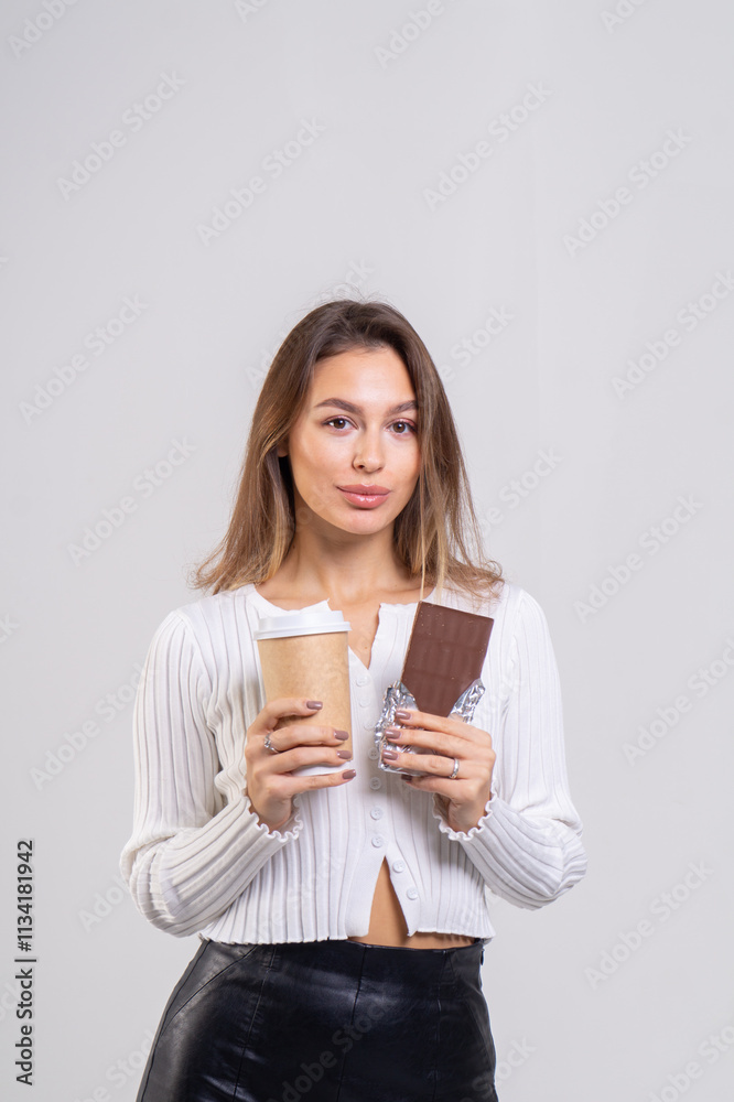 Attractive brunette young woman holding a cofee cup and chocolate on a white background. Copy space, close-up portrait Attractive brunette young woman holding a cofee cup and chocolate on a white background. Copy space, close-up portrait