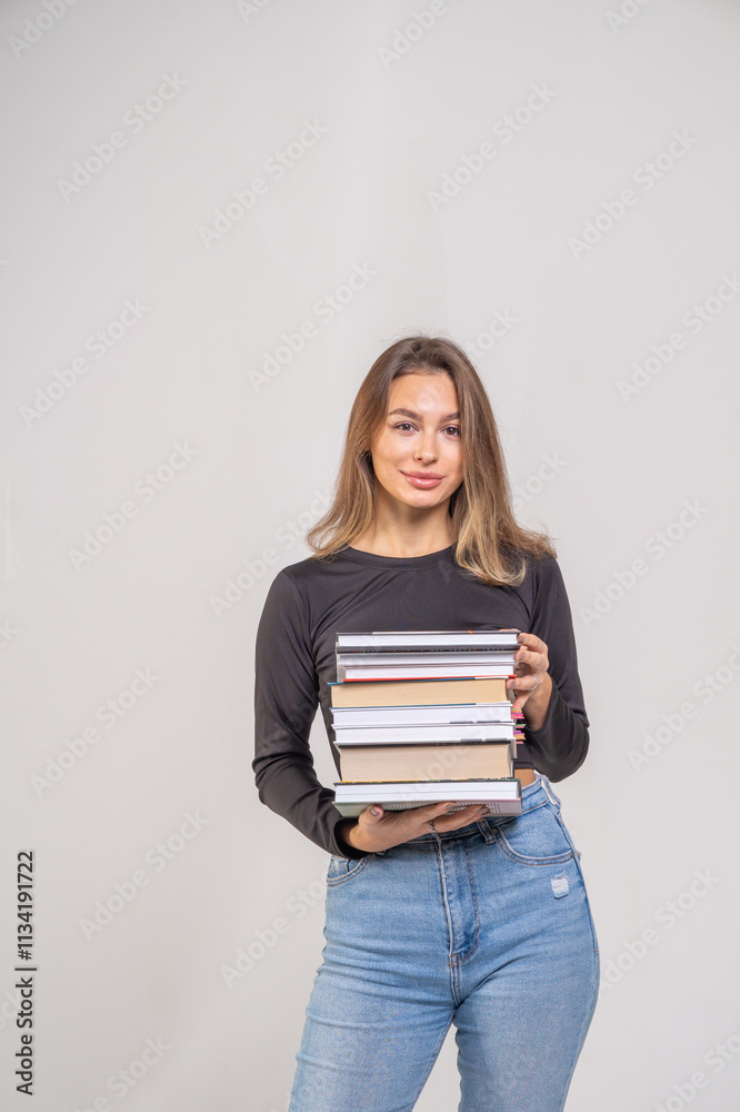 Young cute smiling girl with a stack of books on a white background. Copy space, chest portrait Young cute smiling girl with a stack of books on a white background. Copy space, chest portrait