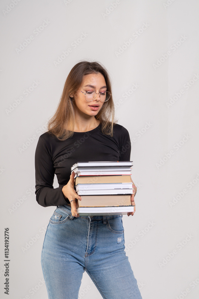 Young cute smiling girl with a stack of books on a white background. Copy space, chest portrait Young cute smiling girl with a stack of books on a white background. Copy space, chest portrait