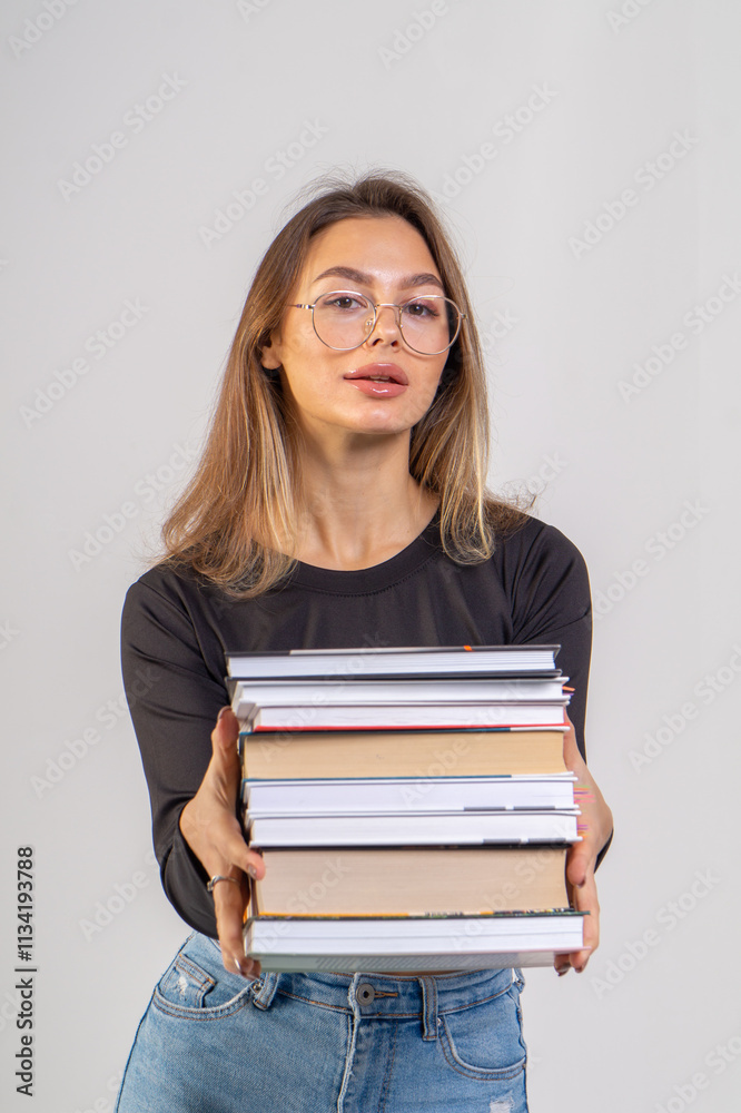 Young cute smiling girl with a stack of books on a white background. Copy space, chest portrait Young cute smiling girl with a stack of books on a white background. Copy space, chest portrait