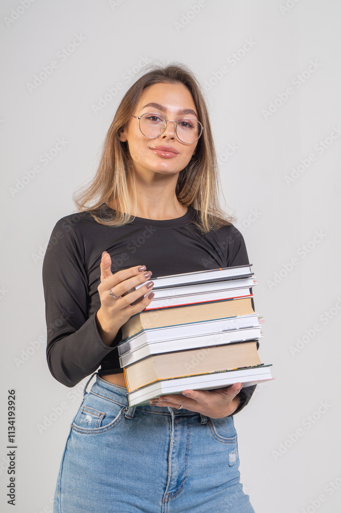 Young cute smiling girl with a stack of books on a white background. Copy space, chest portrait Young cute smiling girl with a stack of books on a white background. Copy space, chest portrait