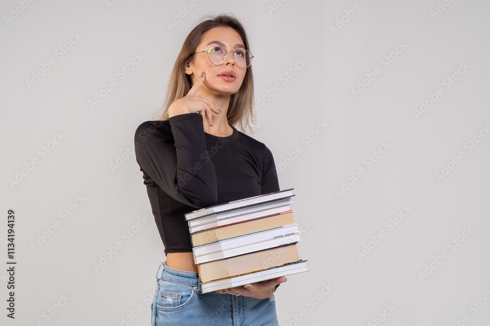 Young cute smiling girl with a stack of books on a white background. Copy space