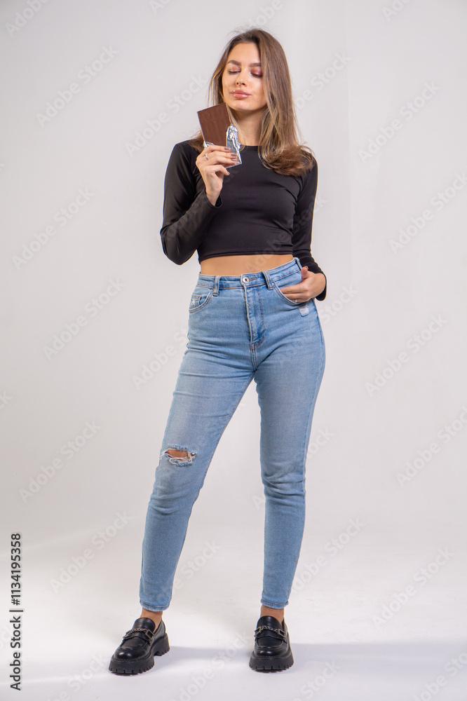 Beautiful young smiling girl with a chocolate bar on a white background, copy space Beautiful young smiling girl with a chocolate bar on a white background, copy space