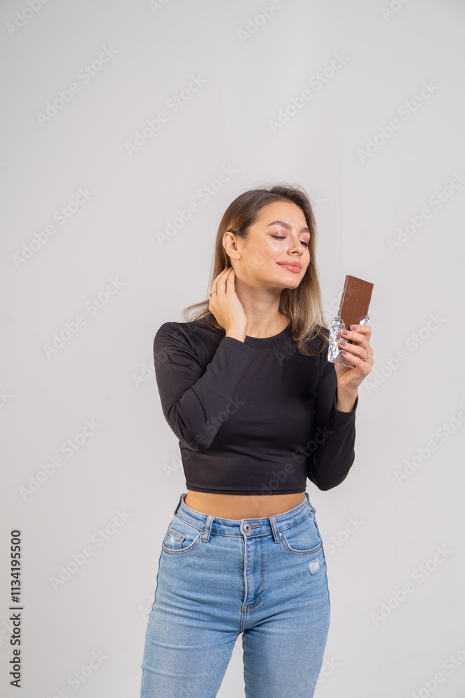 Beautiful young smiling girl with a chocolate bar on a white background, copy space Beautiful young smiling girl with a chocolate bar on a white background, copy space