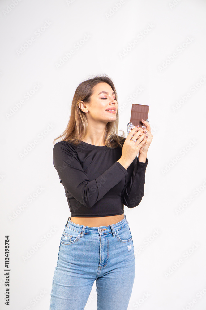 Beautiful young smiling girl with a chocolate bar on a white background, copy space