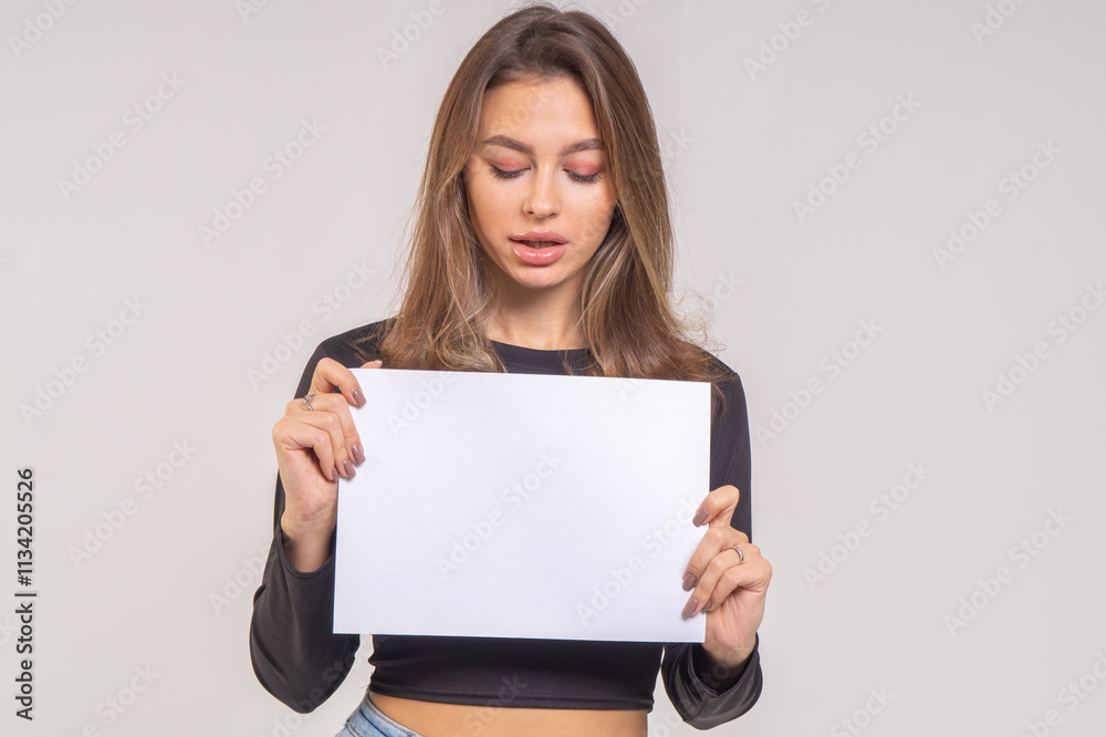 Beautiful young smiling brunette with a sheet of paper A4 close-up on a white background Beautiful young smiling brunette with a sheet of paper A4 close-up on a white background