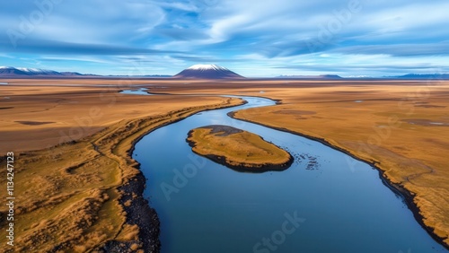 Aerial View of Serene Desert River Winding Through Golden Sands Under Snow-Capped Mountain