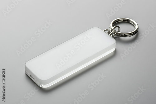 A blank white acrylic keychain with no text or design sitting on an isolated gray background.
