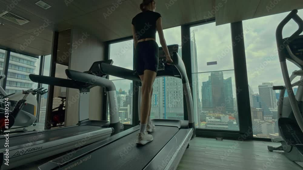 Young woman doing exercises in gym with city view