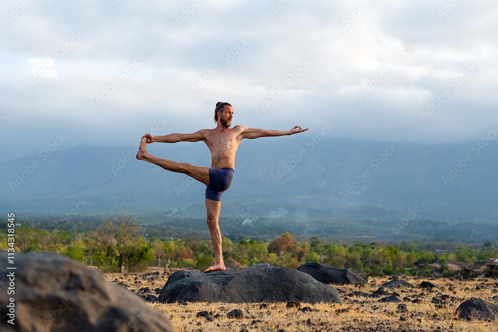 Man Practicing Yoga Meditation Outdoors in Nature with Mountain View.