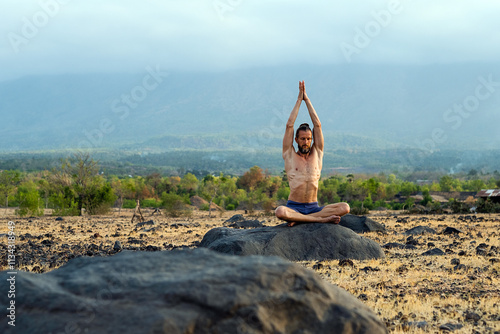 Man Practicing Yoga Meditation Outdoors in Nature with Mountain View.