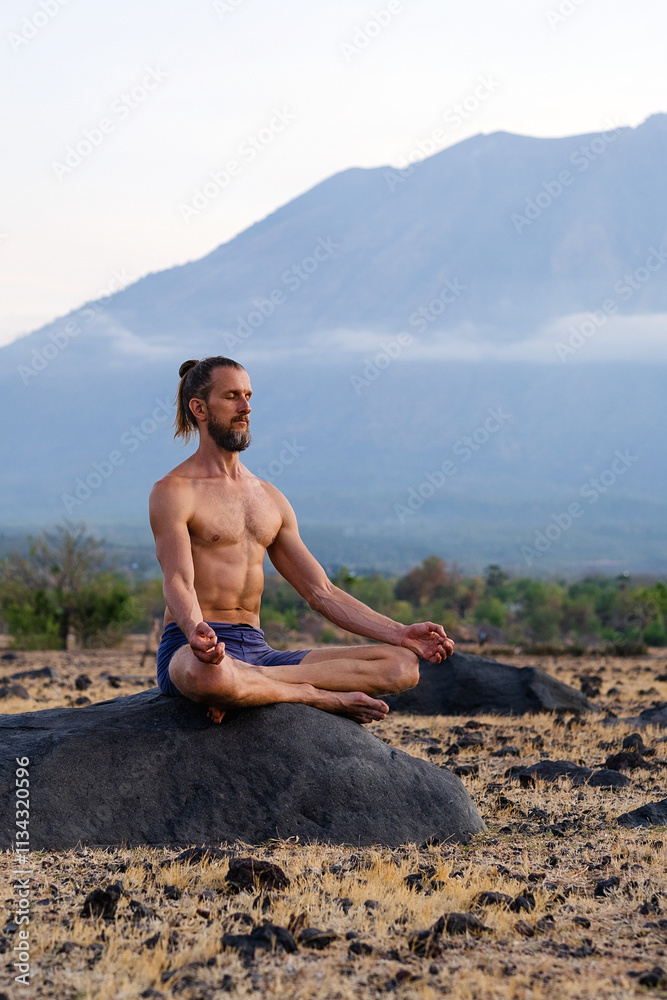 Man Practicing Yoga Meditation Outdoors in Nature with Mountain View. Man Practicing Yoga Meditation Outdoors in Nature with Mountain View.