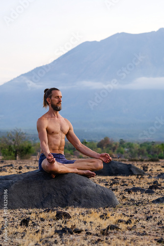 Man Practicing Yoga Meditation Outdoors in Nature with Mountain View.